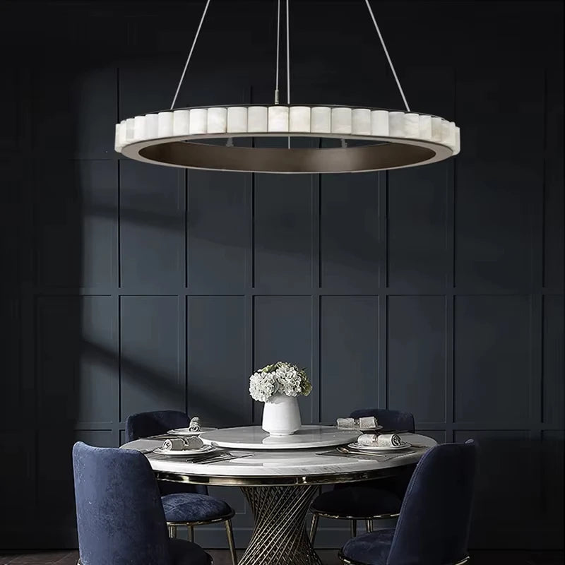 Modern dining room with a round marble table and blue chairs under a stylish pendant light.